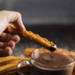 hand-holding-fried-churros-with-chocolate